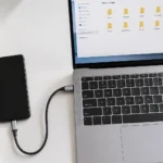 Smartphone connected to laptop with USB-C cable on a clean white desk showing phone to computer connection