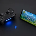 PS4 DualShock 4 controller with glowing blue light bar placed next to a smartphone showing a mobile game, connected via Bluetooth